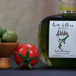 Botella de aceite virgen extra ecológico de 200 ml junto a dos tomates de huerta y aceitunas de verdeo